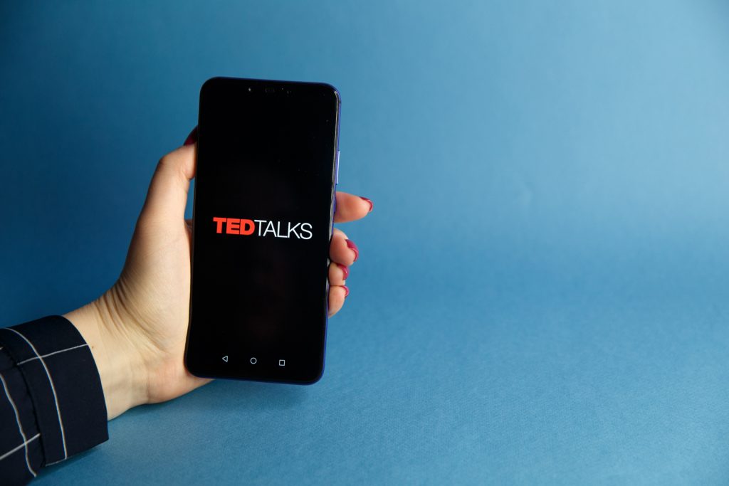 woman holding smartphone with ted talks on screen